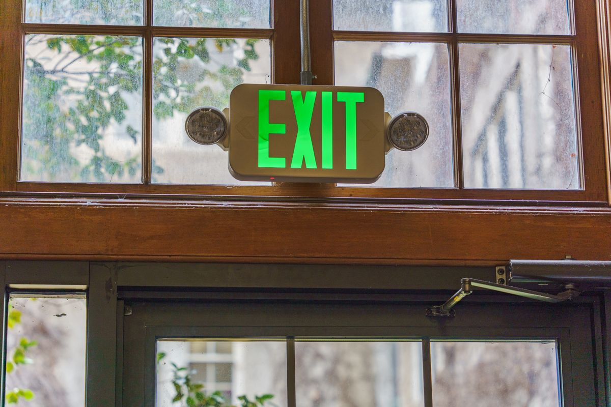 Illuminated exit sign with emergency light heads above a doorway