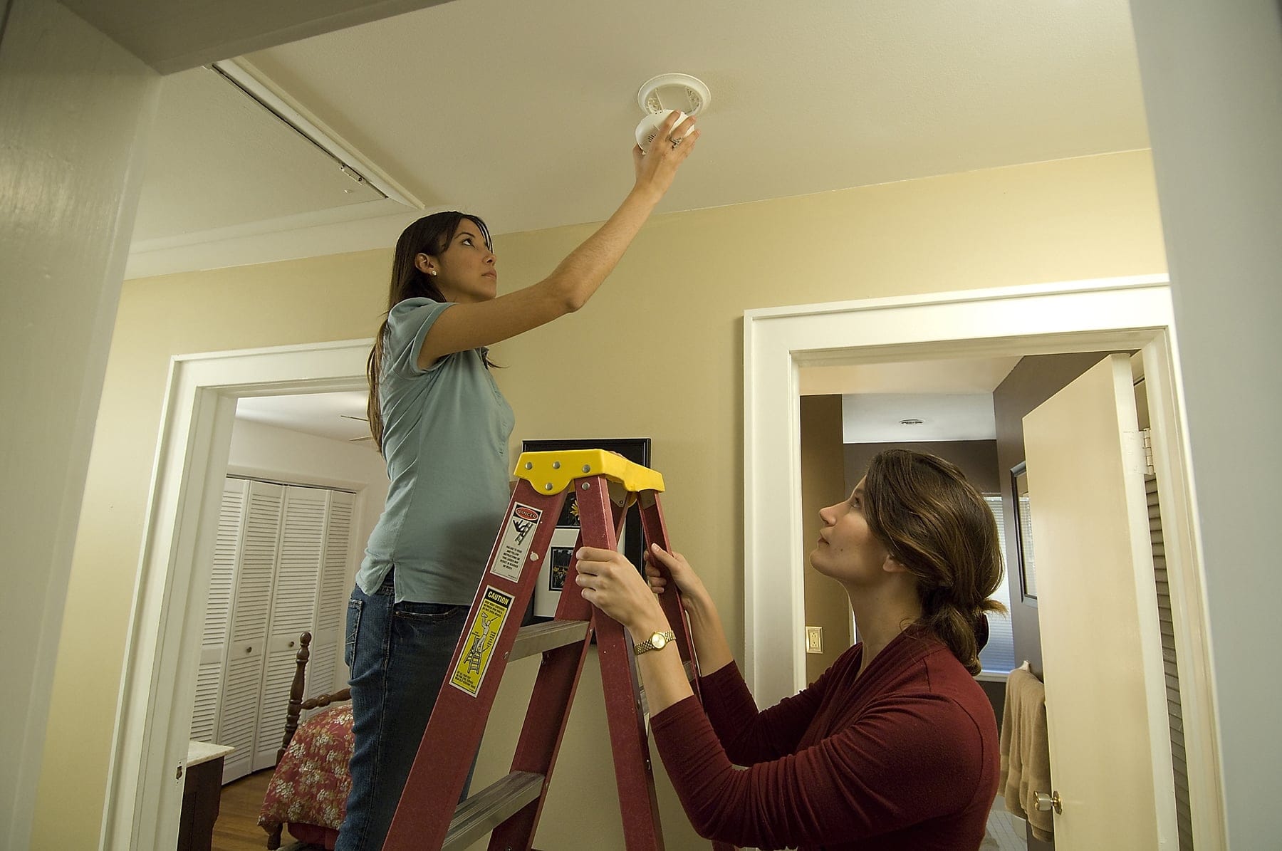 People installing a smoke alarm in a home — illustrative stock photograph